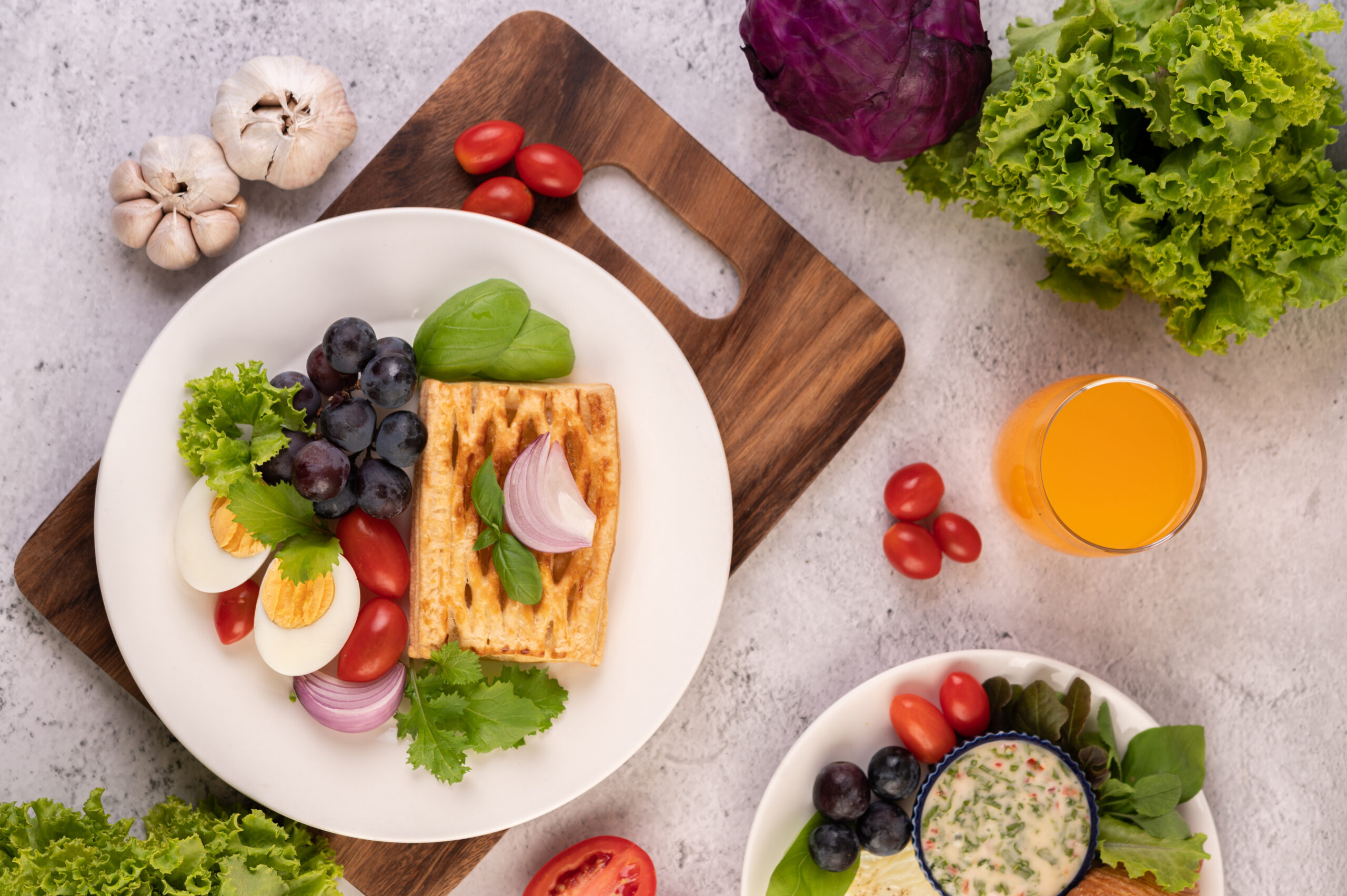 Breakfast consists of bread, boiled eggs, black grape salad dressing, tomatoes, and sliced ​​onions.